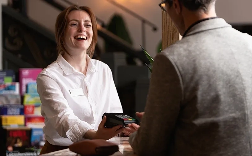 Nahaufnahme einer Person, die eine Kreditkarte in ein Zahlungsterminal auf einer Marmorarbeitsplatte mit Elavon-Logo einführt.